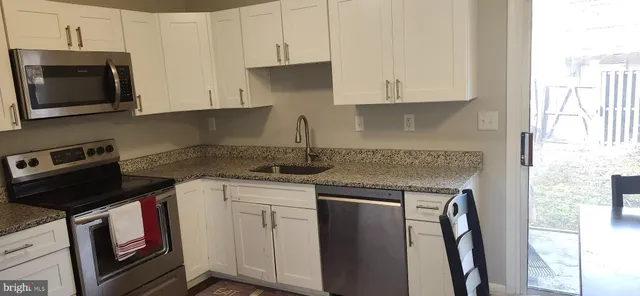 a kitchen with stainless steel appliances granite countertop a stove a sink and a microwave