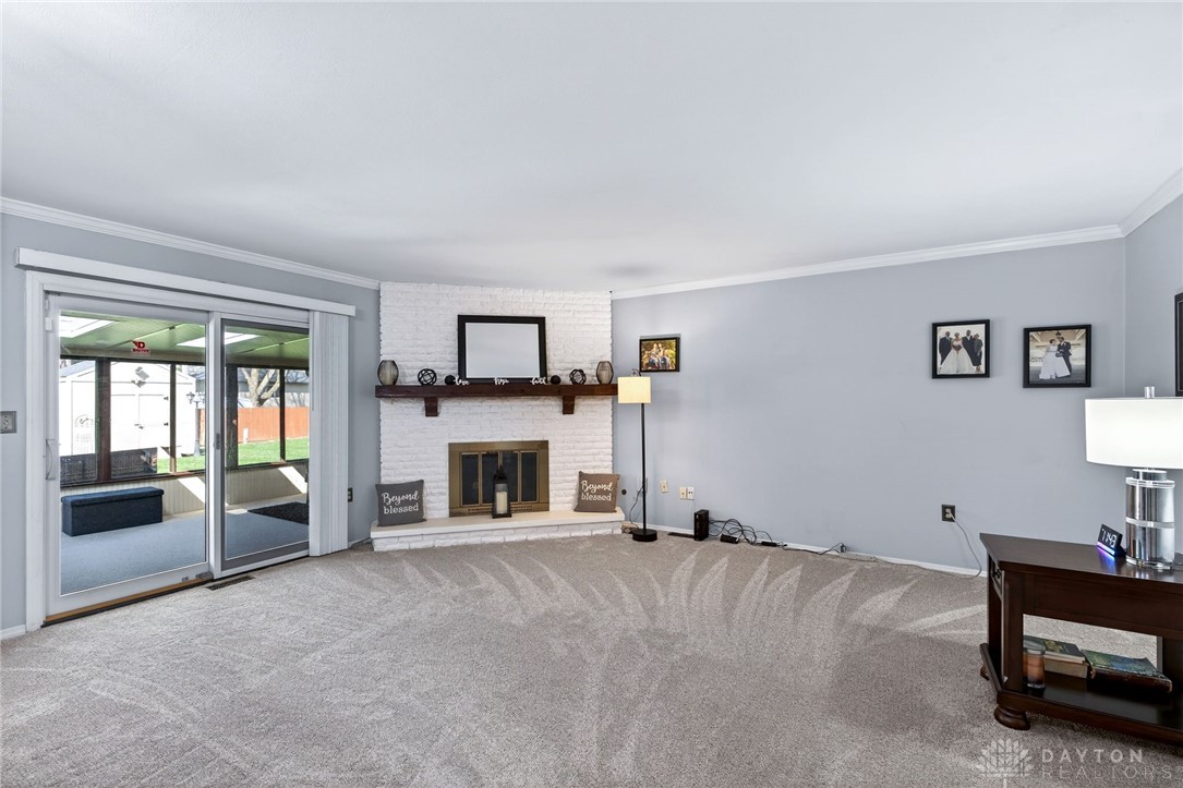 5907 Red Coach Road Dayton, OH 45429 - Photo 20 of 50 This living area features a classic fireplace and glass doors opening to a bright sunroom.