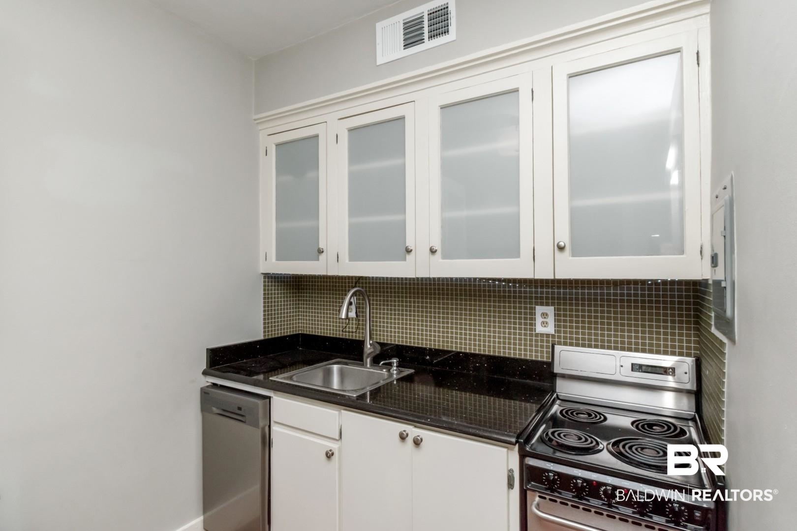 1602 Government Street, Unit 1A Mobile, AL 36604 - Photo 11 of 24 Kitchen featuring appliances with stainless steel finishes, white cabinetry, tasteful backsplash, dark stone countertops, and glass insert cabinets