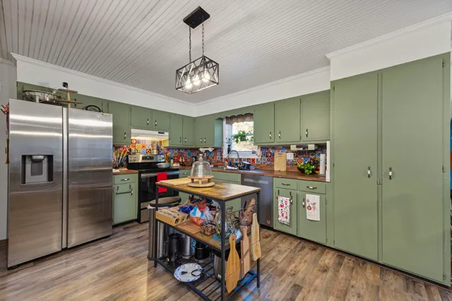 a kitchen with stainless steel appliances granite countertop a refrigerator a stove and a wooden floors