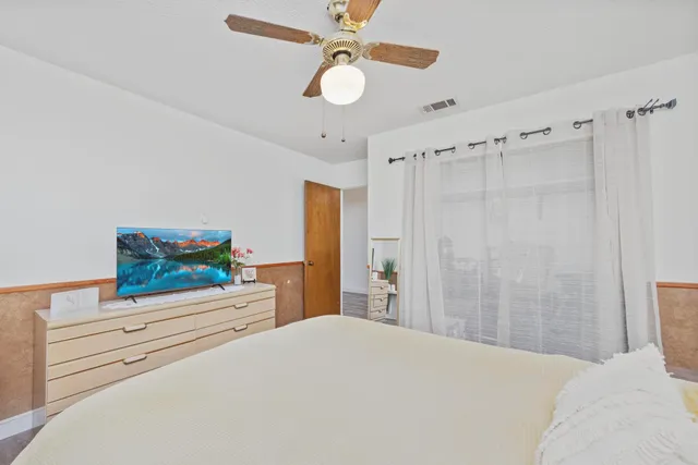 a bedroom with a bed and a flat tv screen on dresser