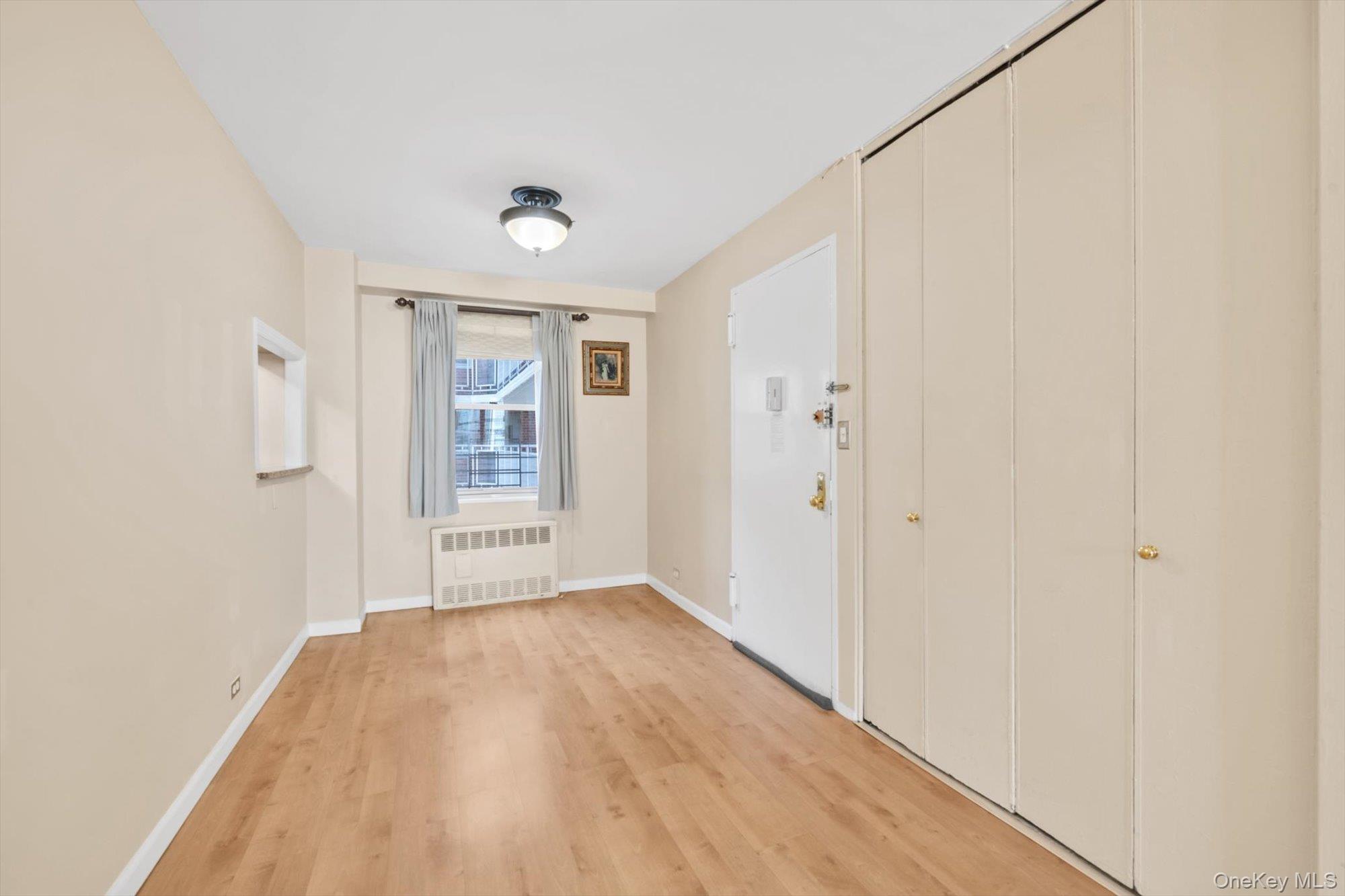 61-15 97th Street, Unit 12A Queens, NY 11374 - Photo 3 of 25 a view of an empty room with wooden floor and a window