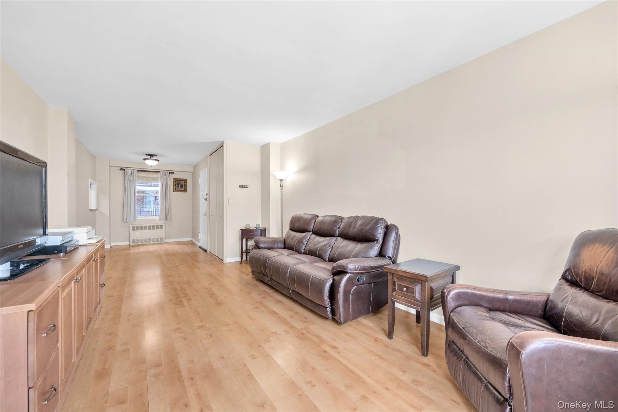 61-15 97th Street, Unit 12A Queens, NY 11374 - Photo 6 of 25 a living room with furniture and a flat screen tv