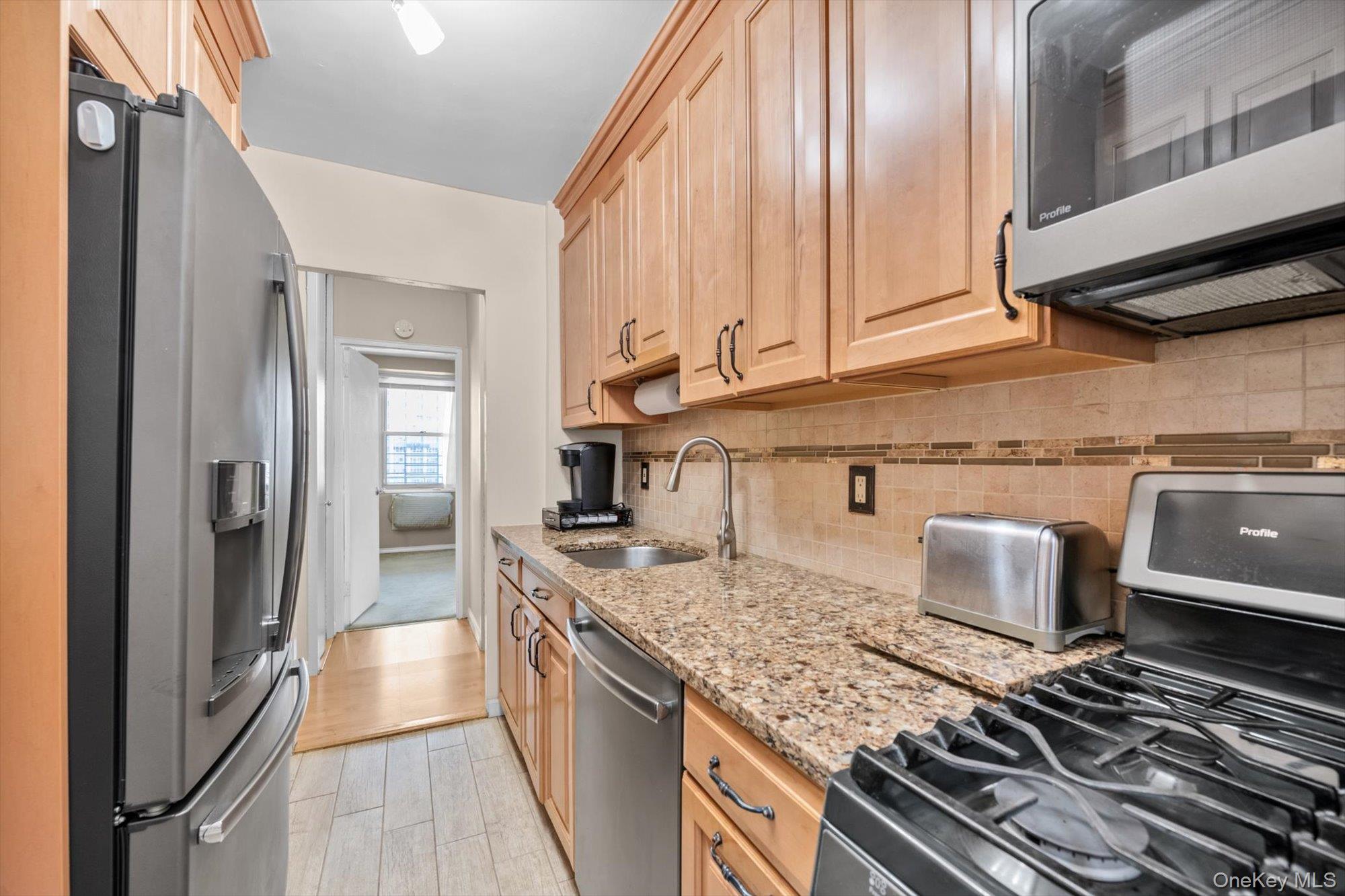61-15 97th Street, Unit 12A Queens, NY 11374 - Photo 7 of 25 a kitchen with stainless steel appliances granite countertop a sink and a stove