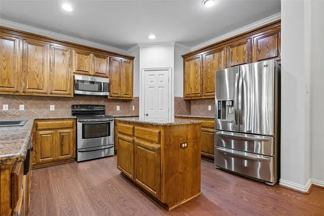 a kitchen with stainless steel appliances granite countertop a refrigerator stove top oven and sink