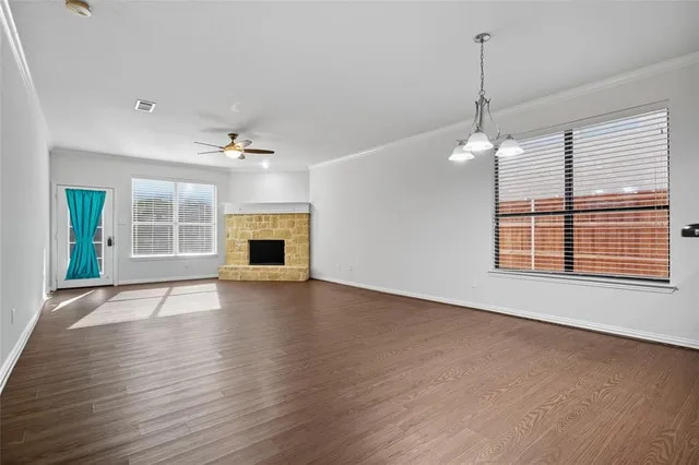a view of an empty room with wooden floor fireplace and a window