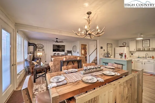a view of a dining room with furniture a kitchen and chandelier