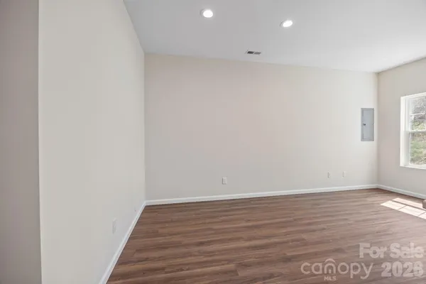 a view of an empty room with a window and wooden floor