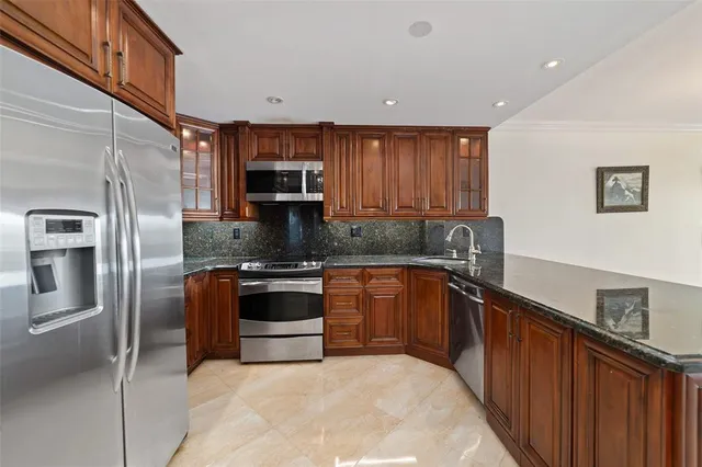a kitchen with stainless steel appliances granite countertop a refrigerator sink and stove
