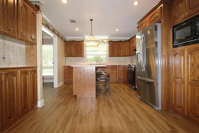 a kitchen with stainless steel appliances granite countertop a refrigerator a stove top oven a sink dishwasher and white cabinets with wooden floor