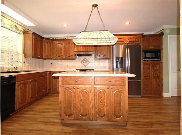 a kitchen with stainless steel appliances granite countertop a sink a stove a refrigerator cabinets and wooden floor