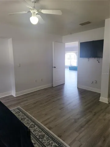 an empty room with wooden floor cabinet and windows