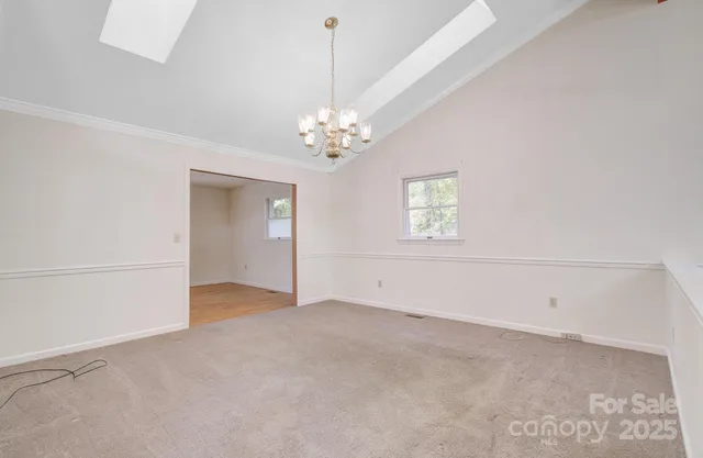 an empty room with chandelier fan and windows