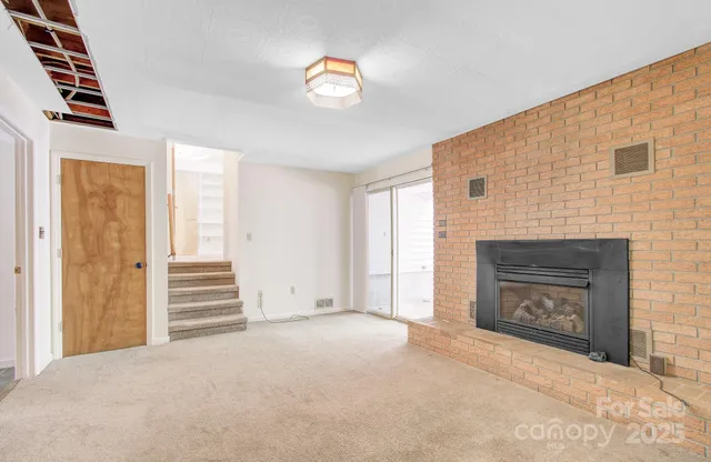 an empty room with windows fireplace and sink