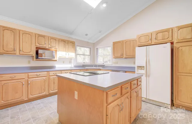 a kitchen with granite countertop a refrigerator a stove a sink and white cabinets