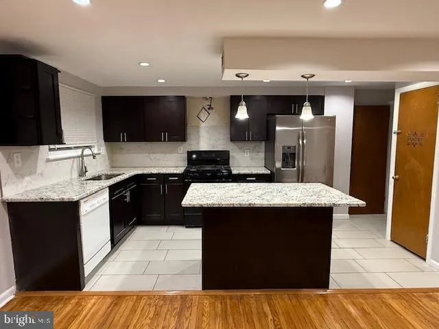 a kitchen with stainless steel appliances kitchen island granite countertop a stove a sink dishwasher and a refrigerator
