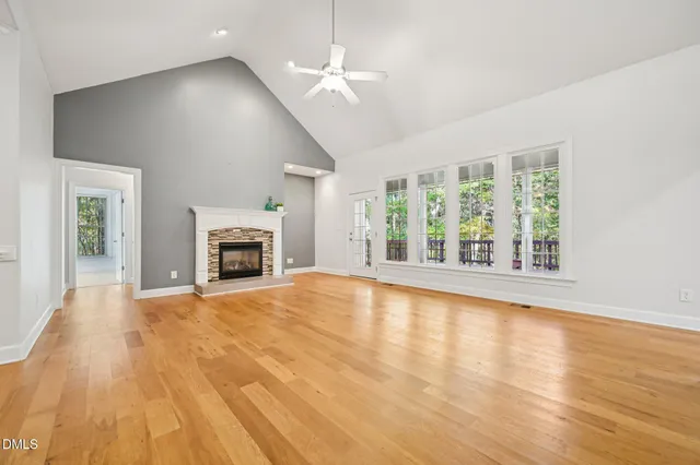 an empty room with wooden floor fireplace and windows