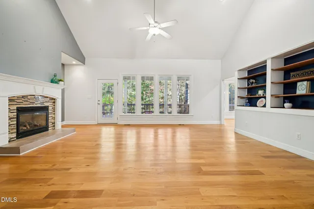 wooden floor in an empty room with a fireplace and a window