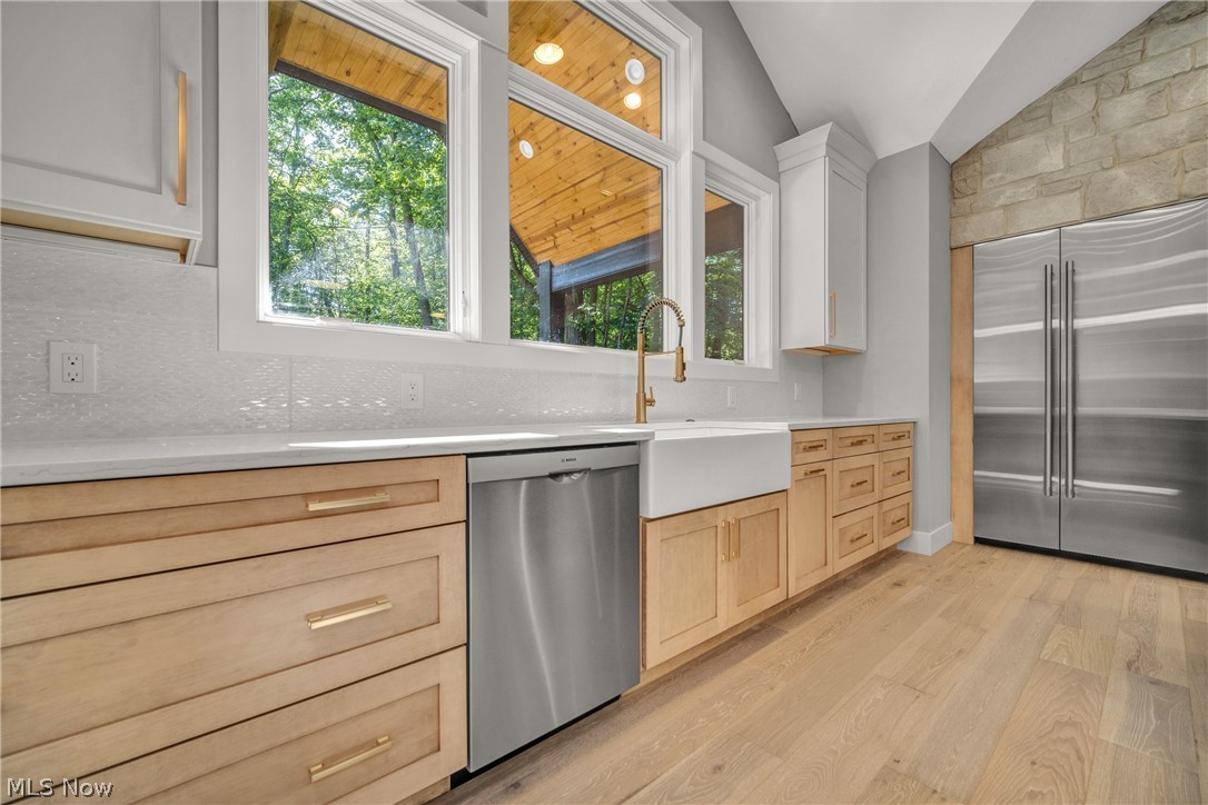 4009 Brainard Road Beachwood, OH 44122 - Photo 19 of 50 Kitchen featuring light brown cabinetry, stainless steel appliances, light wood flooring, vaulted ceiling, and backsplash