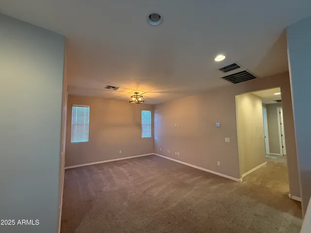 an empty room with chandelier fan and windows