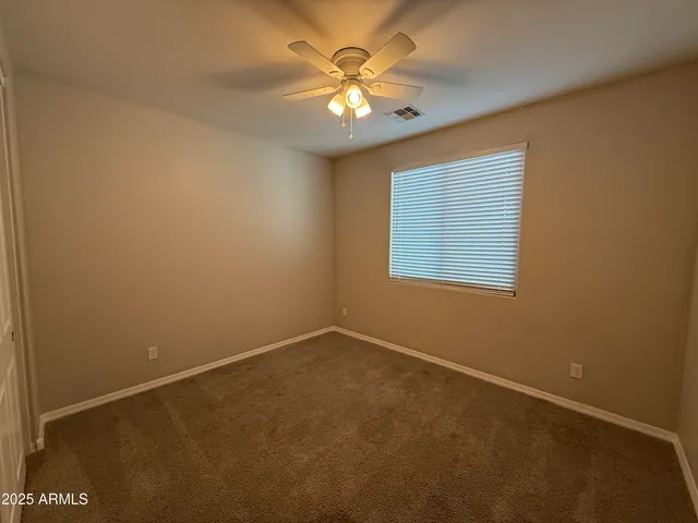 an empty room with a chandelier fan and windows