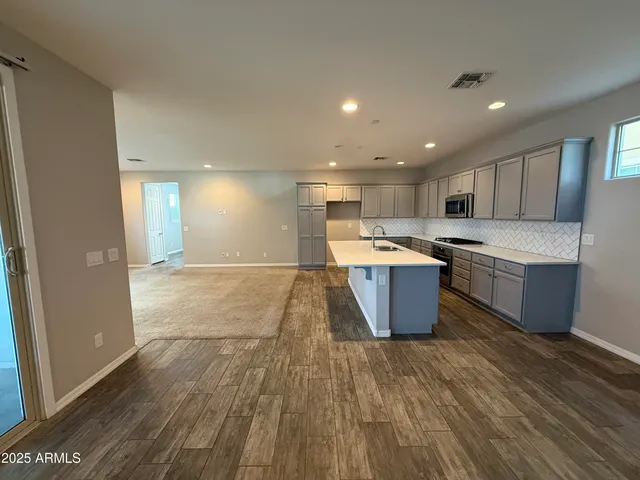 a large kitchen with kitchen island a sink wooden floor and stainless steel appliances