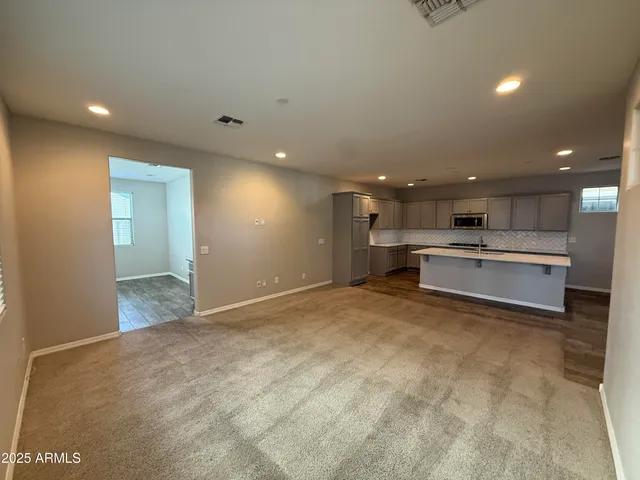 a view of kitchen with kitchen island a sink wooden floor and living room view
