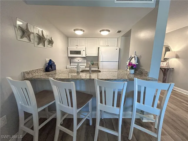 a dining room with stainless steel appliances kitchen island granite countertop a dining table chairs and a refrigerator