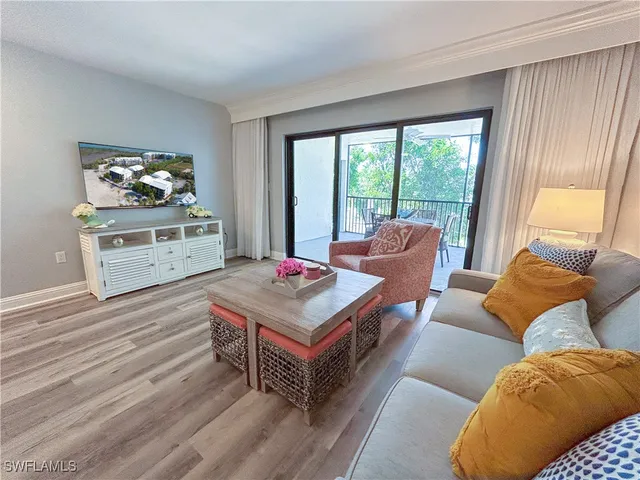 a living room with furniture a flat screen tv and a floor to ceiling window