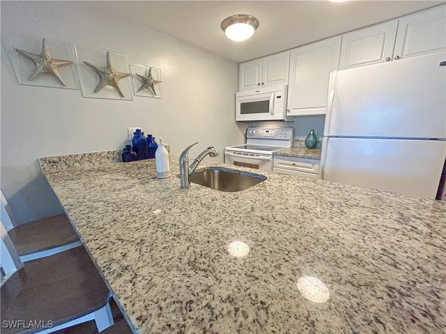 a kitchen with stainless steel appliances granite countertop a sink refrigerator and cabinets
