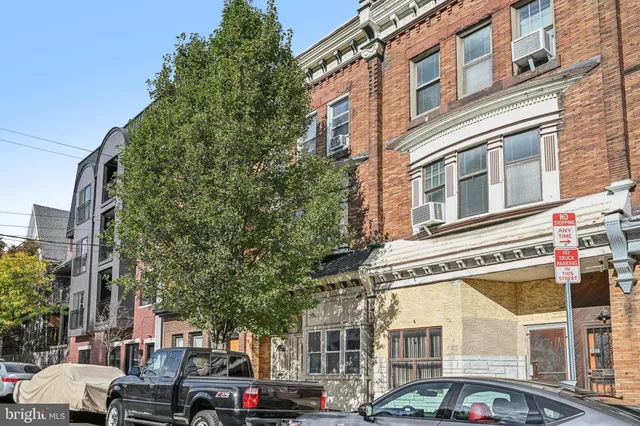 a front view of a building with lot of cars and trees