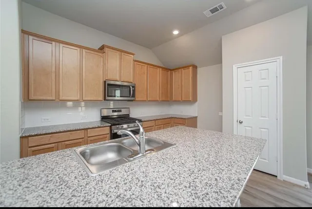 a kitchen with stainless steel appliances granite countertop a sink stove and microwave