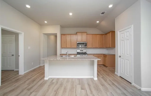 a kitchen with stainless steel appliances granite countertop a hardwood floor sink stove and granite counter top