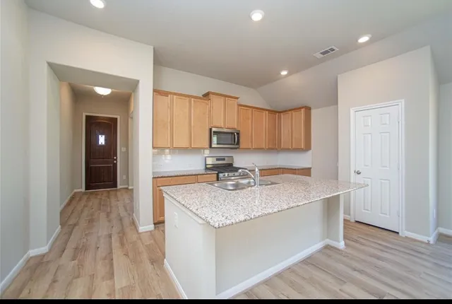a kitchen with kitchen island granite countertop wooden cabinets a sink and dishwasher