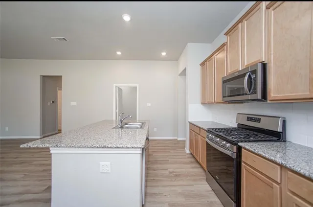 a kitchen with stainless steel appliances granite countertop a stove a sink and a microwave
