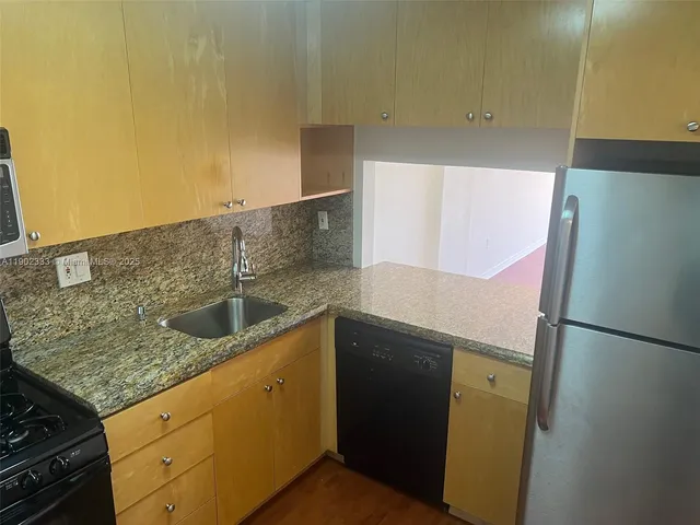a kitchen with stainless steel appliances granite countertop a sink and a refrigerator