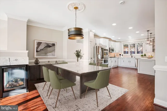 a kitchen with stainless steel appliances granite countertop a stove a sink a dining table and chairs with wooden floor