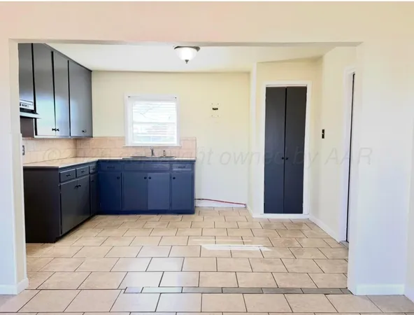a view of an empty room with window and cabinet