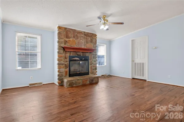 a view of an empty room with wooden floor fireplace and a window