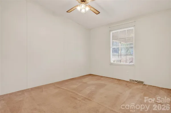 an empty room with a chandelier fan and windows