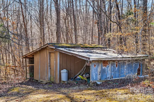 a view of wooden house with large trees and wooden fence