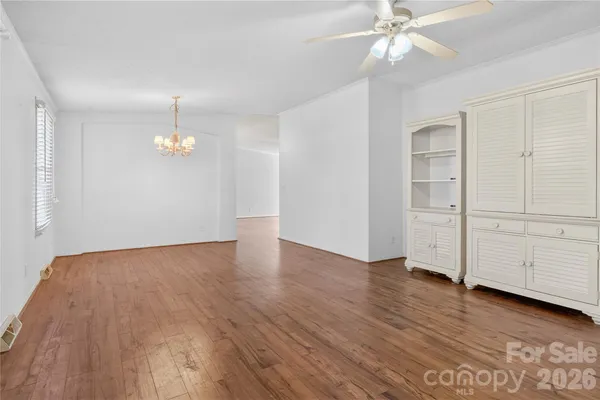 an empty room with wooden floor closet and windows