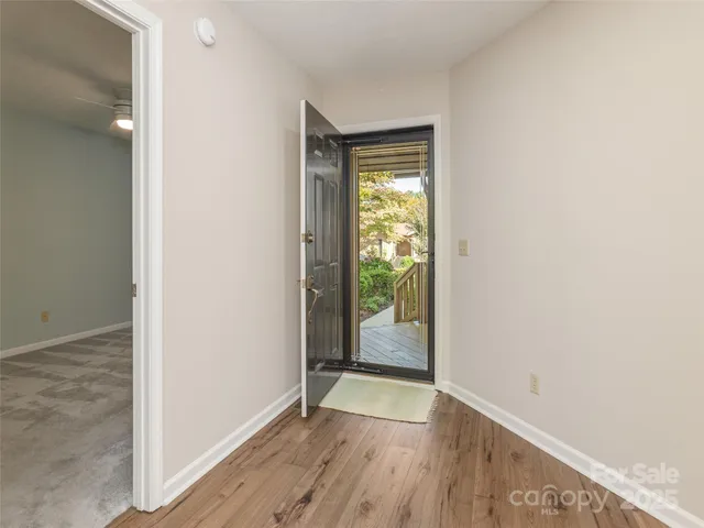 a view of an empty room with wooden floor and a window