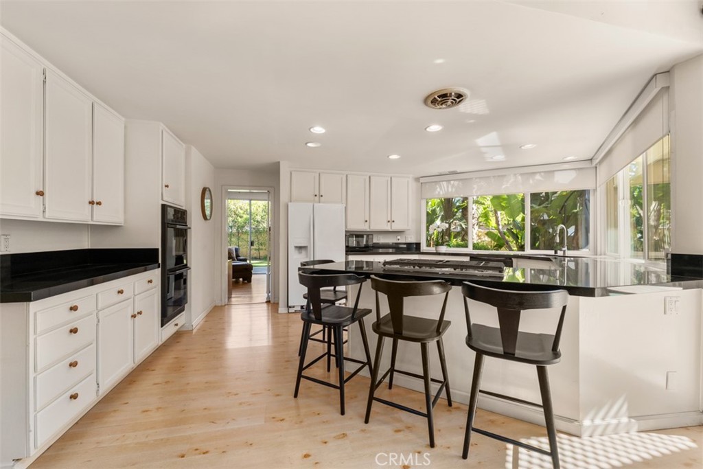 10 Rue Valbonne Newport Beach, CA 92660 - Photo 17 of 66 a kitchen with stainless steel appliances kitchen island granite countertop a table chairs sink and cabinets