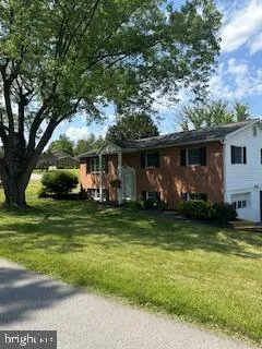 a view of a big house with a big yard and potted plants and large trees