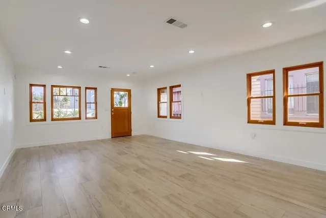 an empty room with wooden floor and windows