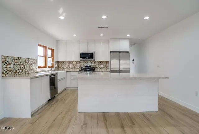a kitchen with granite countertop white cabinets a sink and appliances
