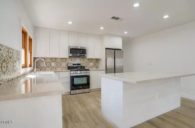 a kitchen with stainless steel appliances granite countertop a stove a sink and a refrigerator