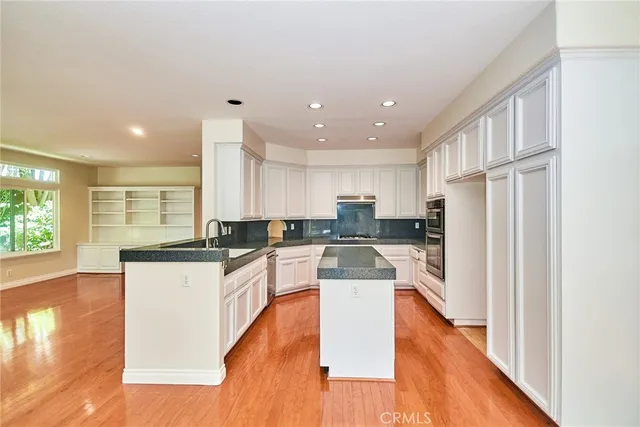 a kitchen with kitchen island a sink a stove a refrigerator and white cabinets