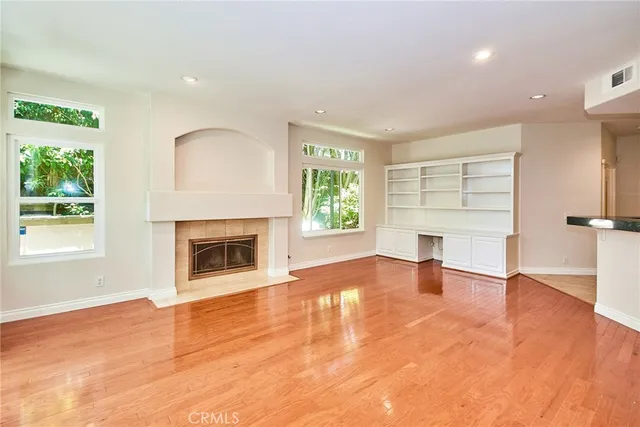 a view of an empty room with wooden floor and a fireplace